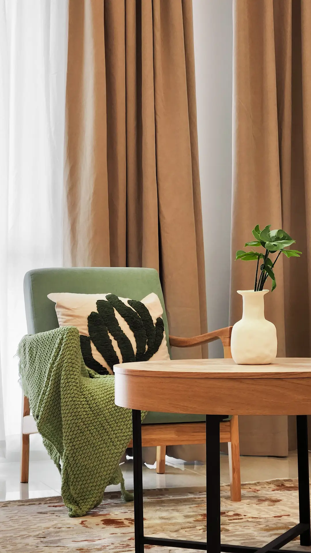 Reading corner with sage armchair, oak side table and tan curtains